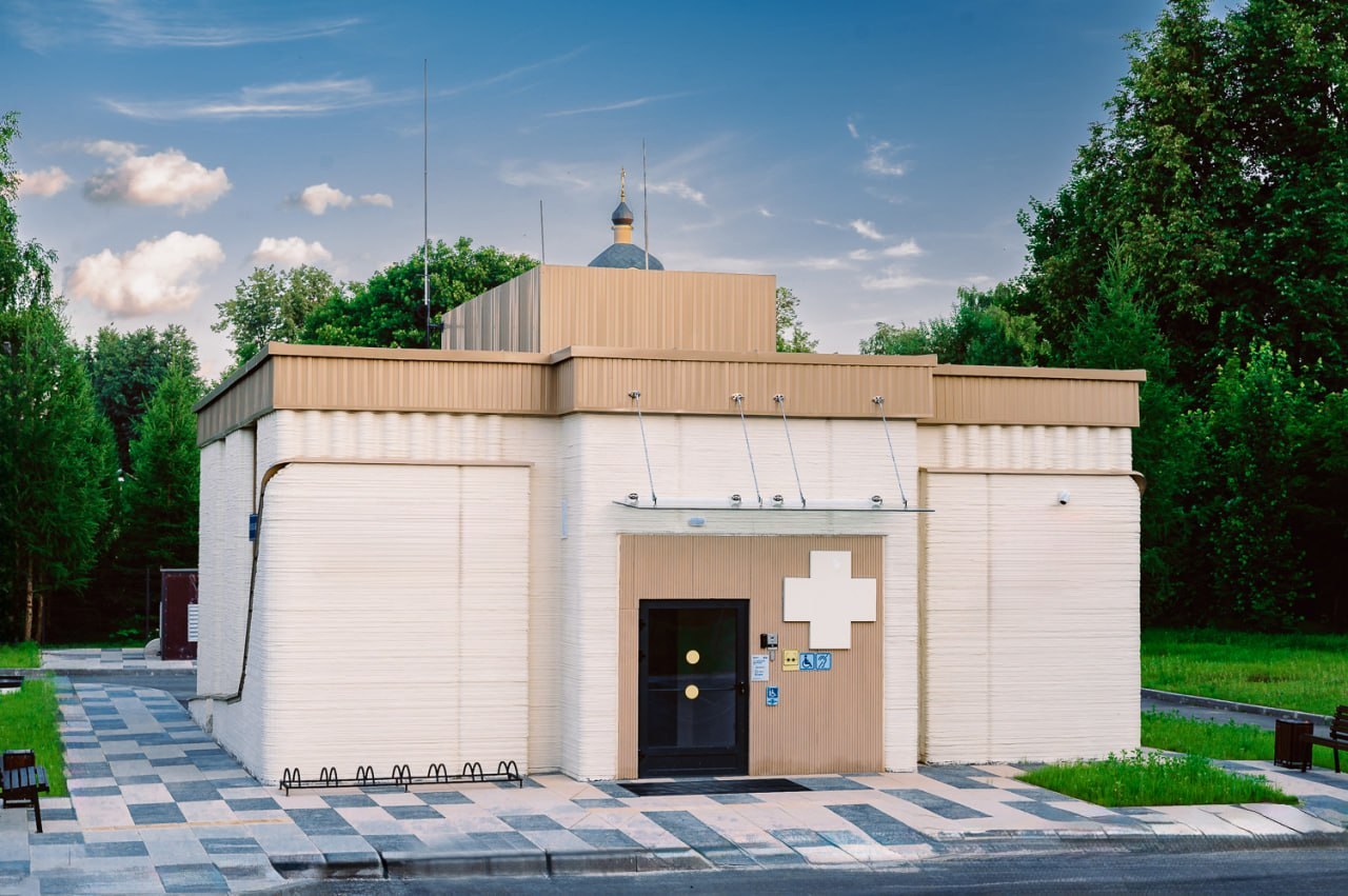 The 3D-Printed Medical Clinic — completed white medical building with a red cross on the facade