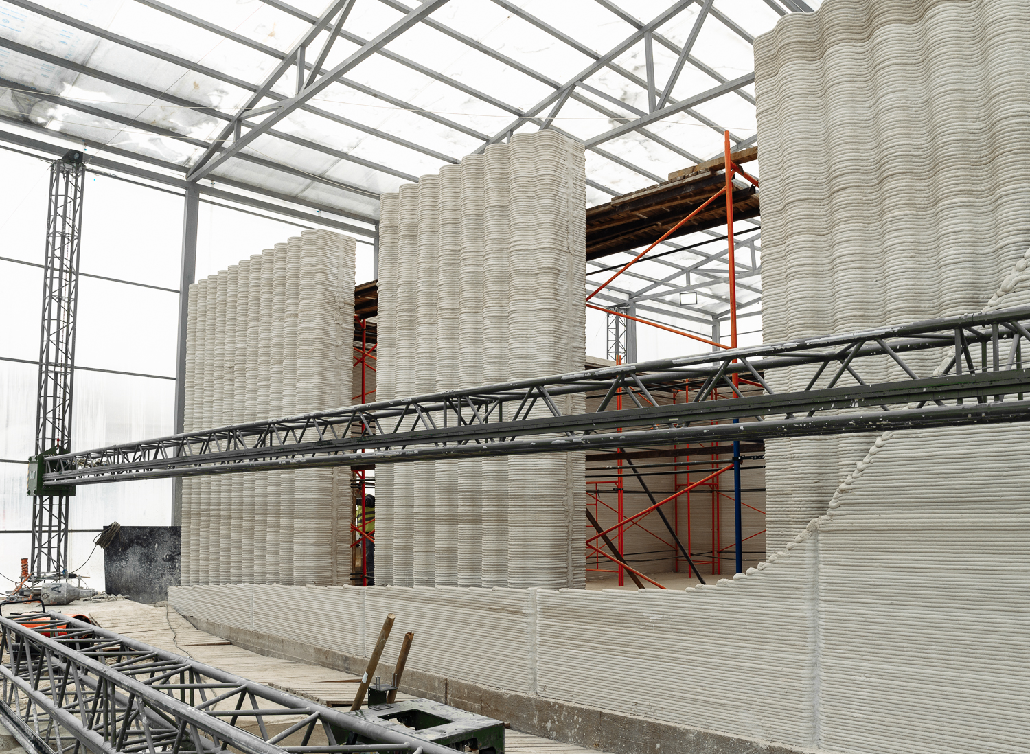 Long 3D-printed concrete walls inside a climate-controlled construction enclosure